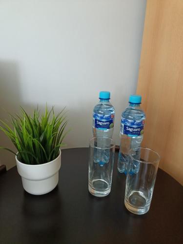 two bottles of water and two glasses on a table at Pokoje pod Świerkiem in Swarzędz