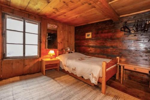 a bedroom with a bed and a wooden wall at Heidi Chalet in Rossinière