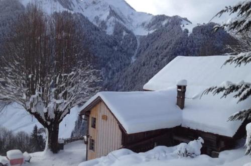 a barn covered in snow in front of a mountain at Heidi Chalet in Rossinière