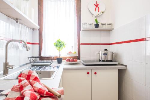 uma cozinha com armários brancos e uma parede com riscas vermelhas e brancas em Casa Dolce Casa Desenzano - 2 passi dal lago em Desenzano del Garda