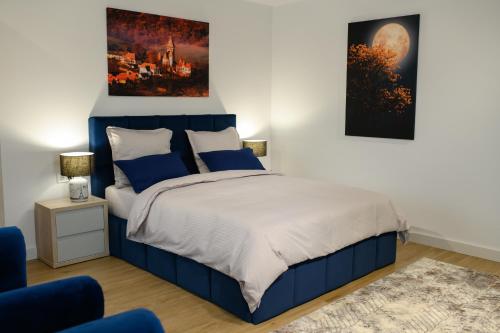 a bedroom with a blue bed and a painting on the wall at Hotel Vila Discret in Satu Mare