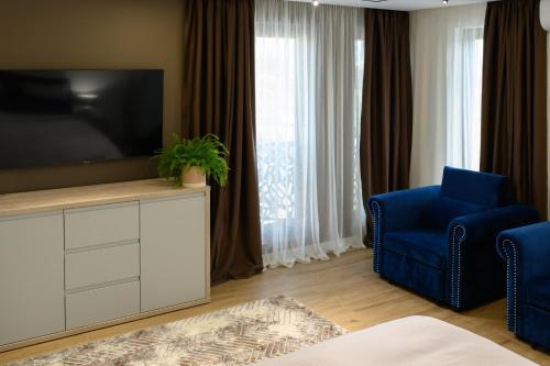 a living room with a tv and a blue chair at Hotel Vila Discret in Satu Mare