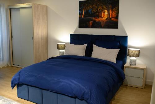 a bedroom with a blue bed with two lamps at Hotel Vila Discret in Satu Mare