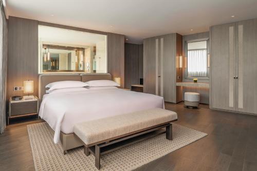 a bedroom with a large white bed and a mirror at Intercontinental Shenzhen Dameisha Resort by IHG in Shenzhen
