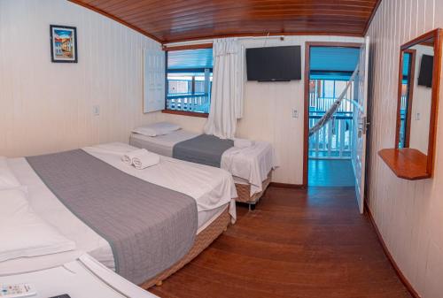 um quarto de hotel com duas camas e uma varanda em Amendoeira Praia Hotel em Morro de São Paulo