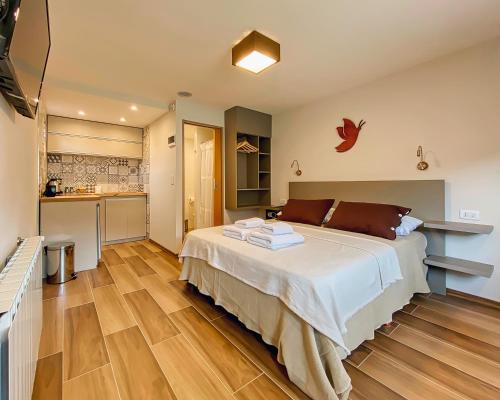 a bedroom with a large bed and a kitchen at APARTS LA FARFALLA in El Chalten