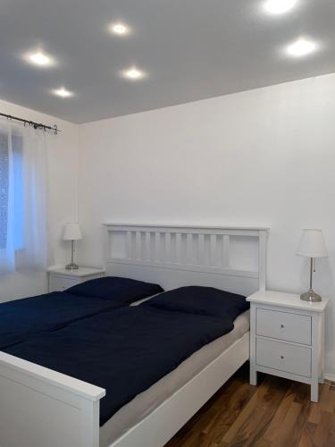 a white bedroom with a large bed and two night stands at Lilli`s Ferienwohnung in Sinsheim