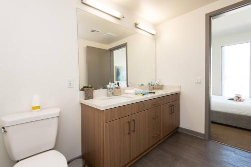 a bathroom with a toilet and a sink and a mirror at Centrally Located Apartments with Free parking in Glendale