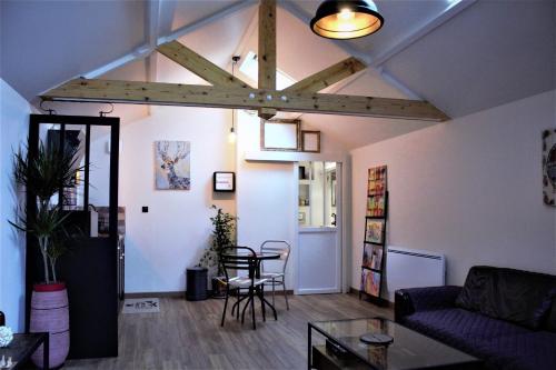 a living room with aamed ceilings and a table and chairs at Style Loft dans une maison au calme in Aubergenville