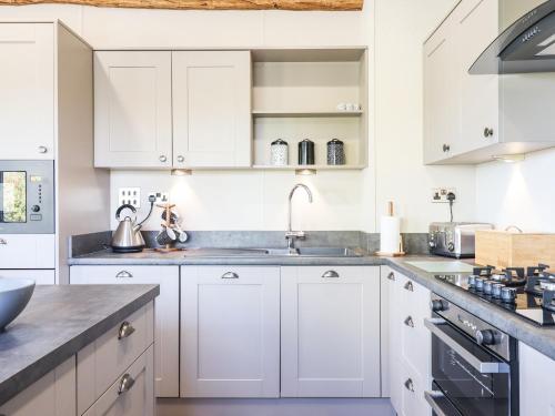 a kitchen with white cabinets and a sink at Cherry Lodge in Newton Abbot