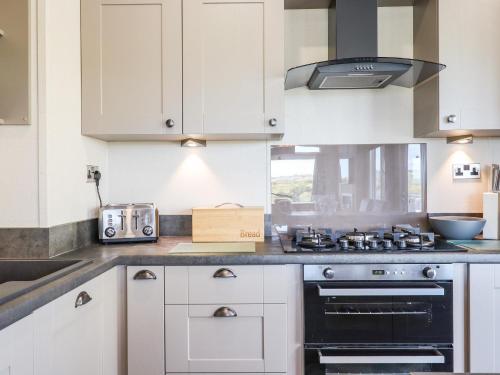 a kitchen with white cabinets and a stove top oven at Cherry Lodge in Newton Abbot