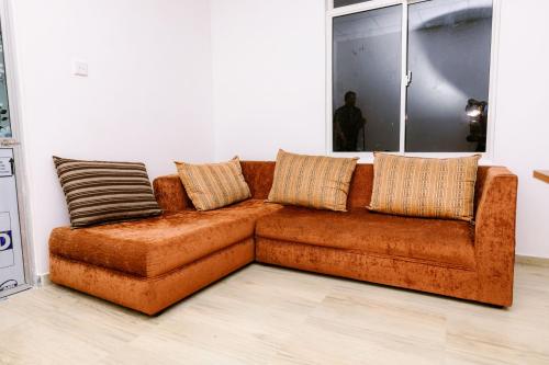 a brown couch with pillows on it in a room at Savenndra Hotel in Ranala