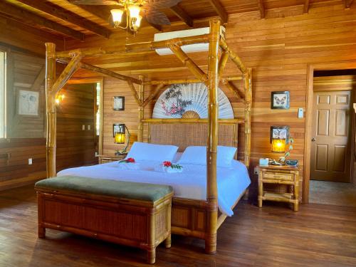 een slaapkamer met een hemelbed in een houten kamer bij Dream Valley Belize in Teakettle Village