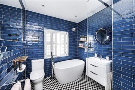 a blue tiled bathroom with a tub and a toilet at St Mary's Cottage in Boston Spa