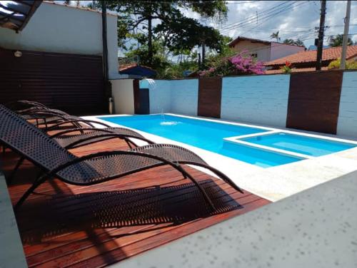 a swimming pool with two chairs next to a swimming pool at Pousada Tribo Ubatuba in Ubatuba