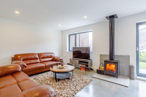 a living room with a leather couch and a fireplace at Svarga Mountain View in Kinlochleven