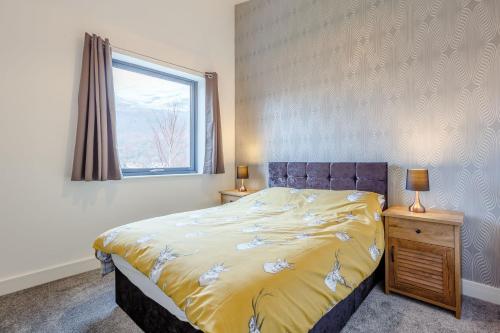 a bedroom with a bed with a yellow blanket and a window at Svarga Mountain View in Kinlochleven