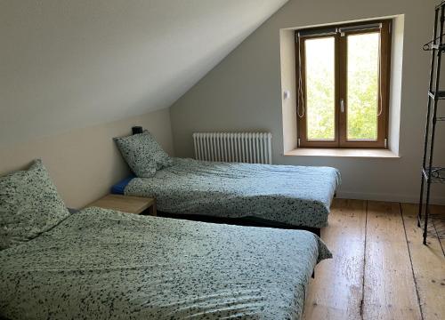 a bedroom with two beds and a window at l'ECURIE pour 6 personnes in Lebétain