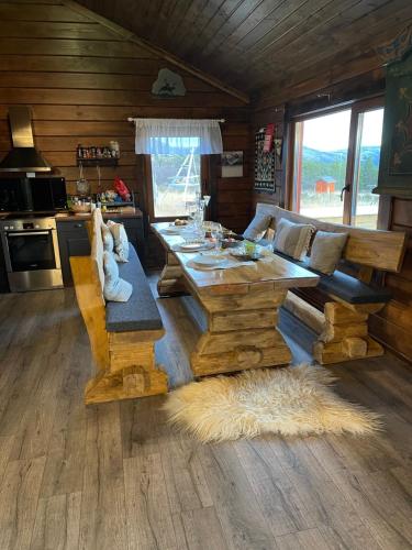 ein Wohnzimmer mit einem Holztisch und einer Küche in der Unterkunft Trollvang in Dovreskogen