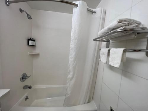 een witte badkamer met een douche en een bad bij Atlantic Motor Inn in Brooklyn