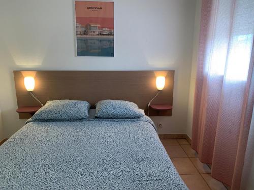 a bedroom with a bed with two pillows and two lamps at T2 Les jardins Gruissan in Gruissan