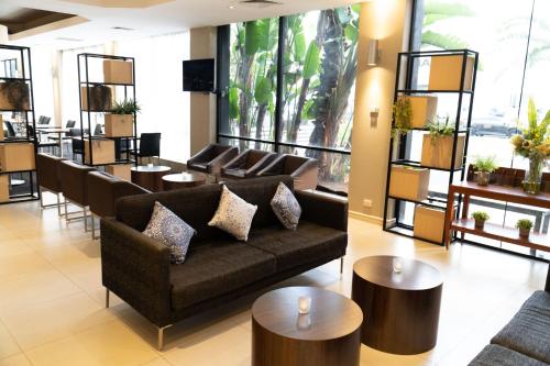 a living room with couches and tables and windows at Holiday Inn Parramatta by IHG in Sydney