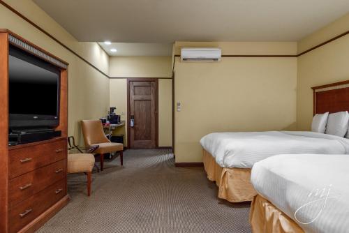 um quarto de hotel com duas camas e uma televisão de ecrã plano em Hotel Seville em Harrison