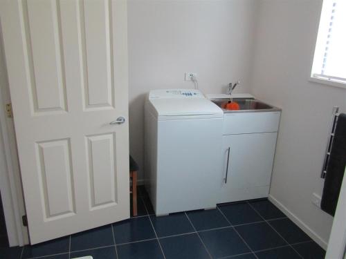 a kitchen with a washing machine and a sink at Cornwallis Palms in Auckland
