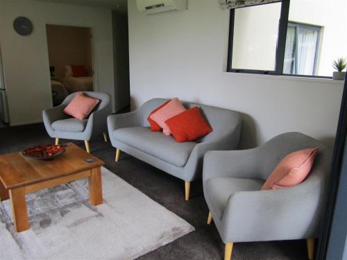 a living room with two chairs and a table at Cornwallis Palms in Auckland