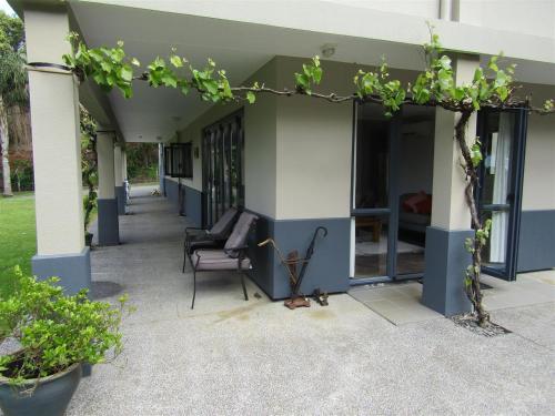 a porch of a house with a chair and some plants at Cornwallis Palms in Auckland
