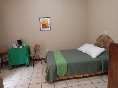 a bedroom with a green bed and a table at Hotel Cibeles Resort in Heredia
