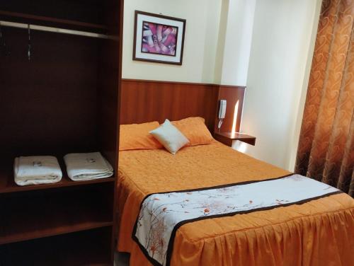 1 dormitorio pequeño con 1 cama con sábanas de color naranja en HOSTAL QENQO en Tacna