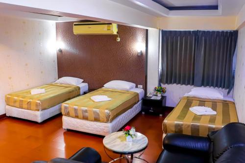a hotel room with two beds and a chair at Visiting Card Hotel & Resort in Bangkok