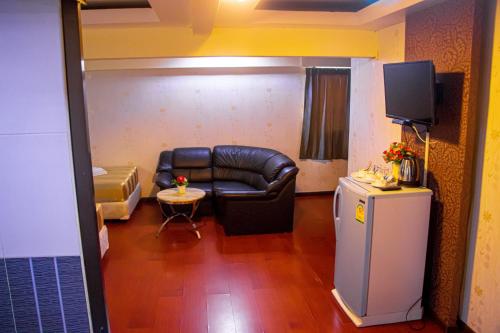 Visiting Card Hotel & Resort في بانكوك: غرفة معيشة مع أريكة جلدية وتلفزيون