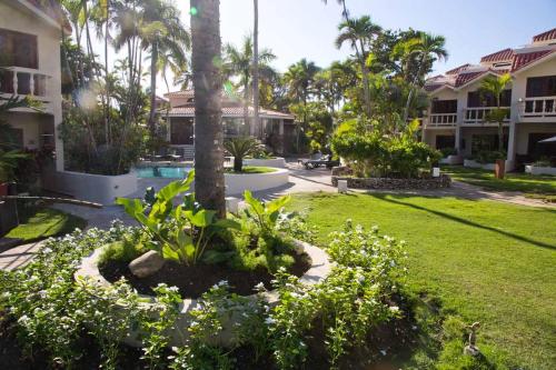 a garden in front of a house with palm trees at CABARETE BEACH HOUSES the NANNY ESTATES in Cabarete