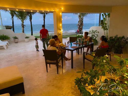 a group of people sitting at a table near the ocean at CABARETE BEACH HOUSES the NANNY ESTATES in Cabarete