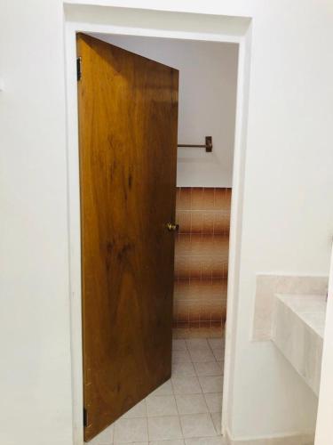 uma porta de madeira numa casa de banho com piso em azulejo em Hotel Los Leones em Palenque