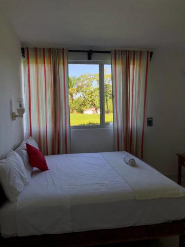 um quarto com uma grande cama branca e uma janela em Hotel Los Leones em Palenque