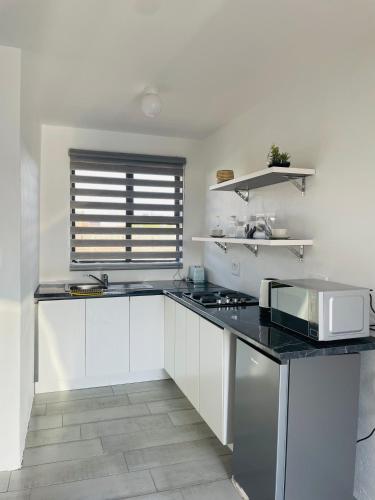 a kitchen with white cabinets and a black counter top at Moh Ville Guest House in Maseru