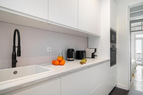 a white kitchen with a sink and oranges on the counter at Brand New Luxury 4-Bed with Riverside Views & AC in Lisbon