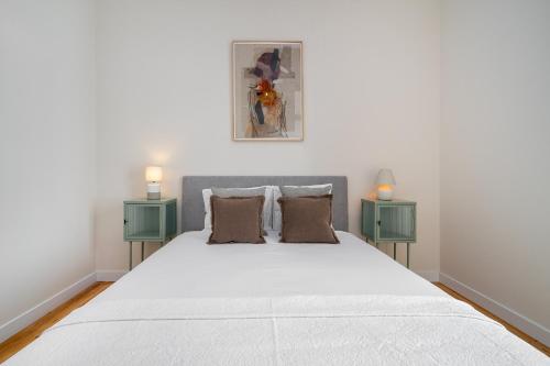 a bedroom with a large white bed with two green night stands at Brand New Luxury 4-Bed with Riverside Views & AC in Lisbon
