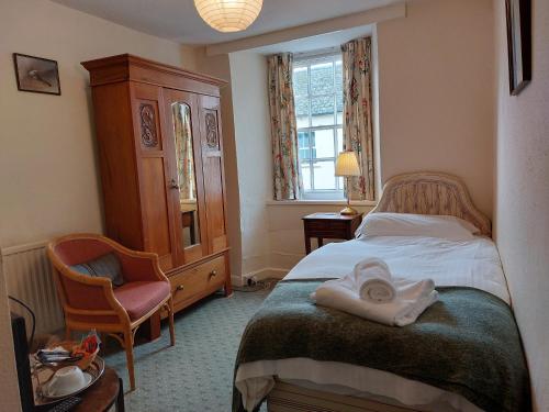 a bedroom with a bed and a chair and a window at Lion Hotel Dulverton in Dulverton