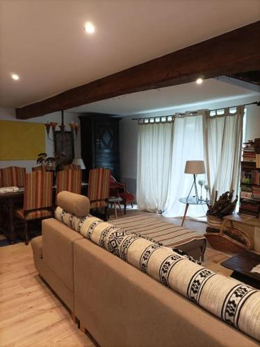 una sala de estar con un gran sofá con almohadas. en Chaumière avec sa toiture recouverte de chaume !!!, en Donnemain-Saint-Mamès