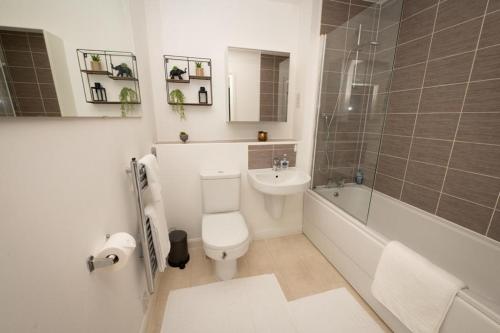 a bathroom with a toilet and a tub and a sink at Grand Station Suite in Wolverhampton