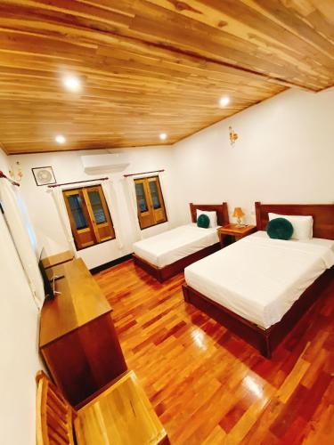 a bedroom with two beds and a wooden floor at Opera Premier Hotel in Luang Prabang