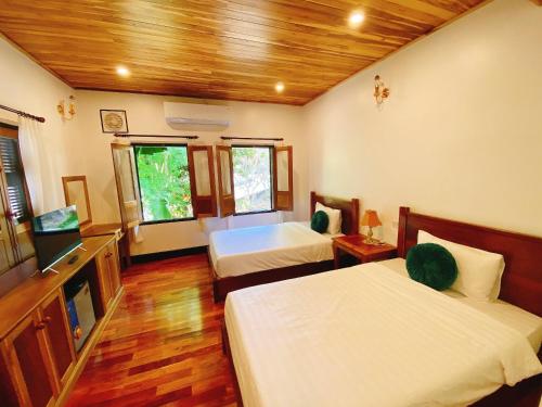 a bedroom with two beds and a television in it at Opera Premier Hotel in Luang Prabang