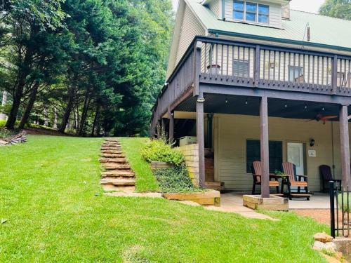 a house with a porch and a lawn next to it at Stay at Rivermist Dahlonega in Dahlonega