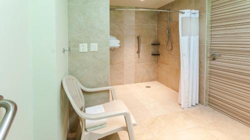 a bathroom with a shower with a chair and a shower curtain at Holiday Inn Coatzacoalcos, an IHG Hotel in Coatzacoalcos