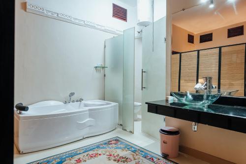 a bathroom with a tub and a sink at Yushili Hotel Kampala in Kampala
