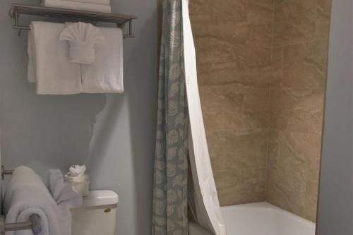 a bathroom with a tub and a shower with towels at Hanalei Bay Resort 8233 in Princeville